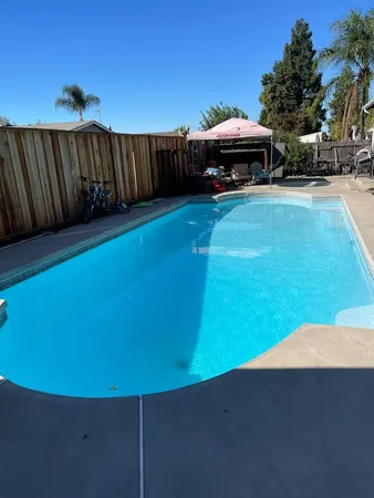 a view of swimming pool with lawn chairs under an umbrella