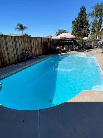 a view of swimming pool with lawn chairs under an umbrella