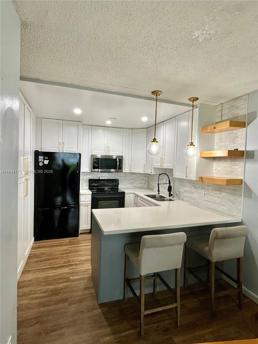 a kitchen with granite countertop a table chairs microwave and cabinets