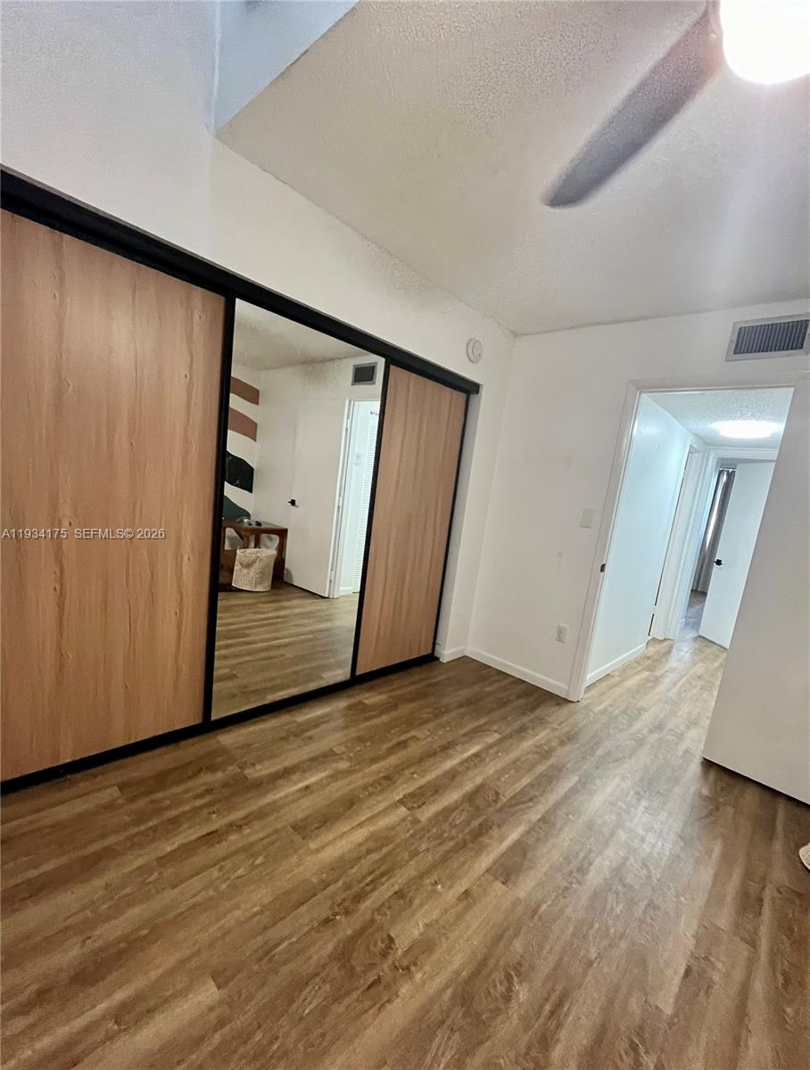 1750 West 56th Street, Unit 211 Hialeah, FL 33012 - Photo 7 of 19 a view of an empty room with wooden floor and a window