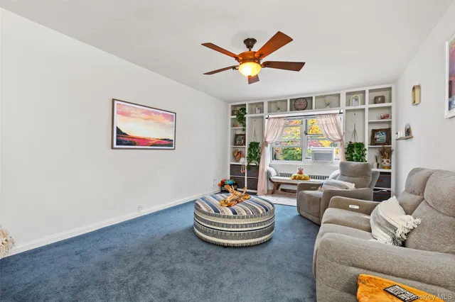 a living room with furniture ceiling fan and a window