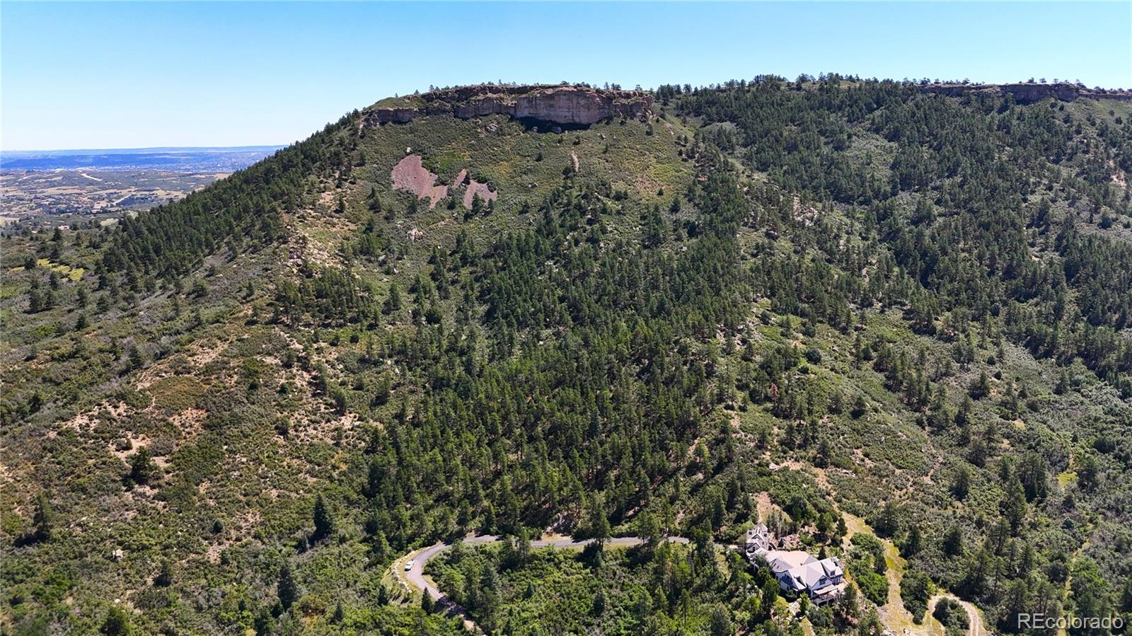 5080 South Perry Park Road Sedalia, CO 80135 - Photo 20 of 39 a view of a houses with a lush green hillside
