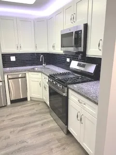 a kitchen with granite countertop a stove top oven microwave and cabinets