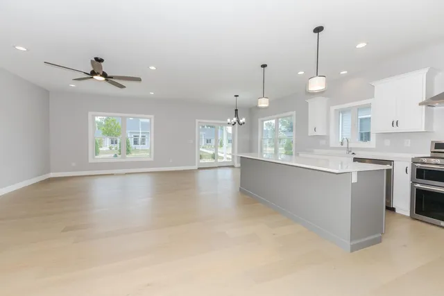 a large kitchen with granite countertop a stove a sink a center island and wooden floor