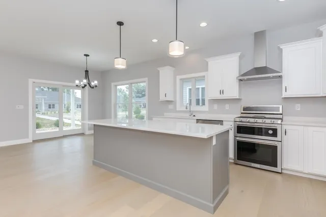 a large kitchen with stainless steel appliances a large counter top a refrigerator a sink and a stove