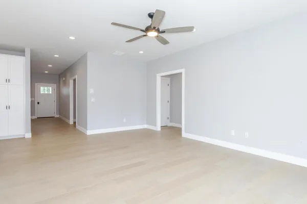 an empty room with windows and ceiling fan