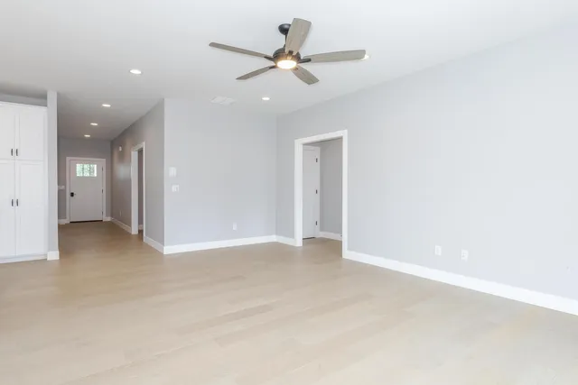 an empty room with windows and ceiling fan