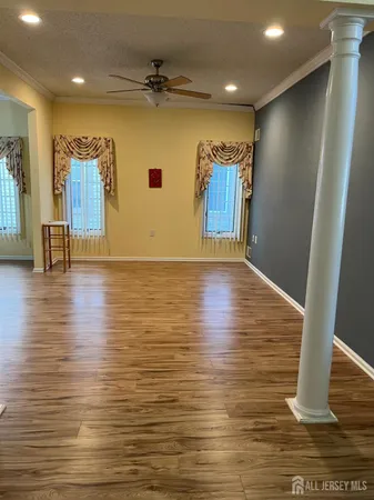 a view of empty room with wooden floor and fan