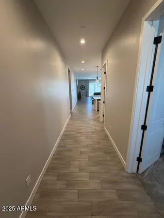 a view of a hallway with wooden floor and a bathroom
