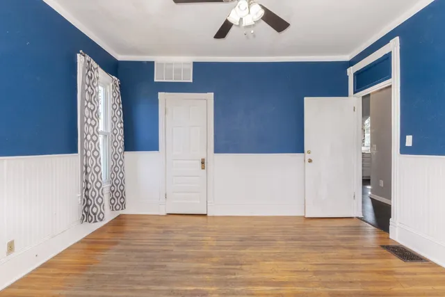 a view of an empty room with window and wooden floor
