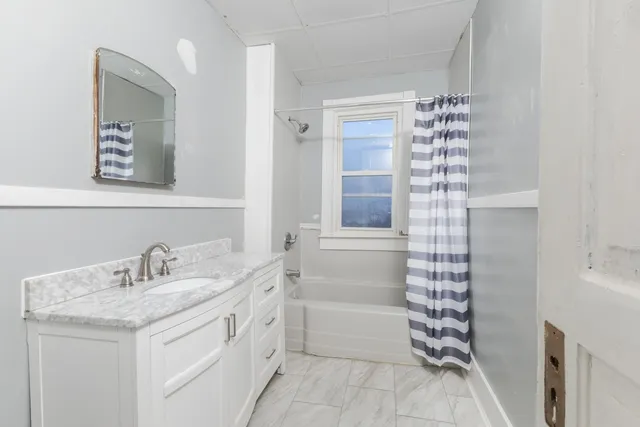a bathroom with a granite countertop sink a mirror and a bathtub