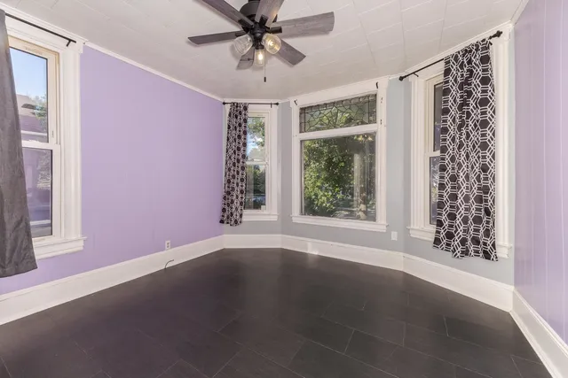 an empty room with windows and fan