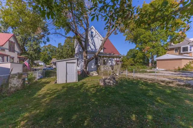 a backyard of a house with plants and large tree