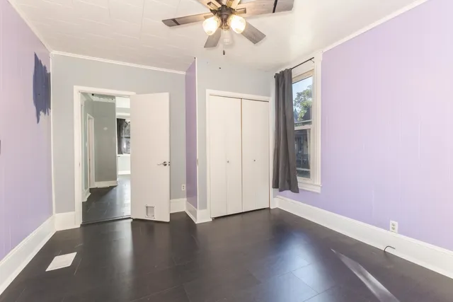 a view of an empty room with wooden floor and a ceiling fan
