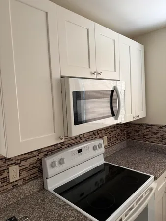 a kitchen with granite countertop white cabinets and stainless steel appliances