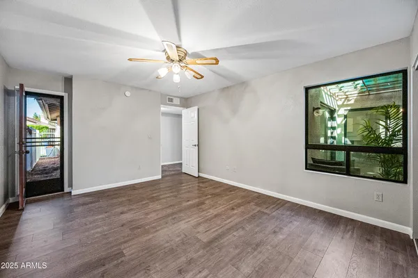 a view of an empty room with a window and wooden floor