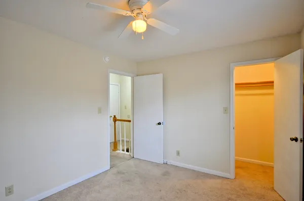 an empty room with closet and a chandelier fan