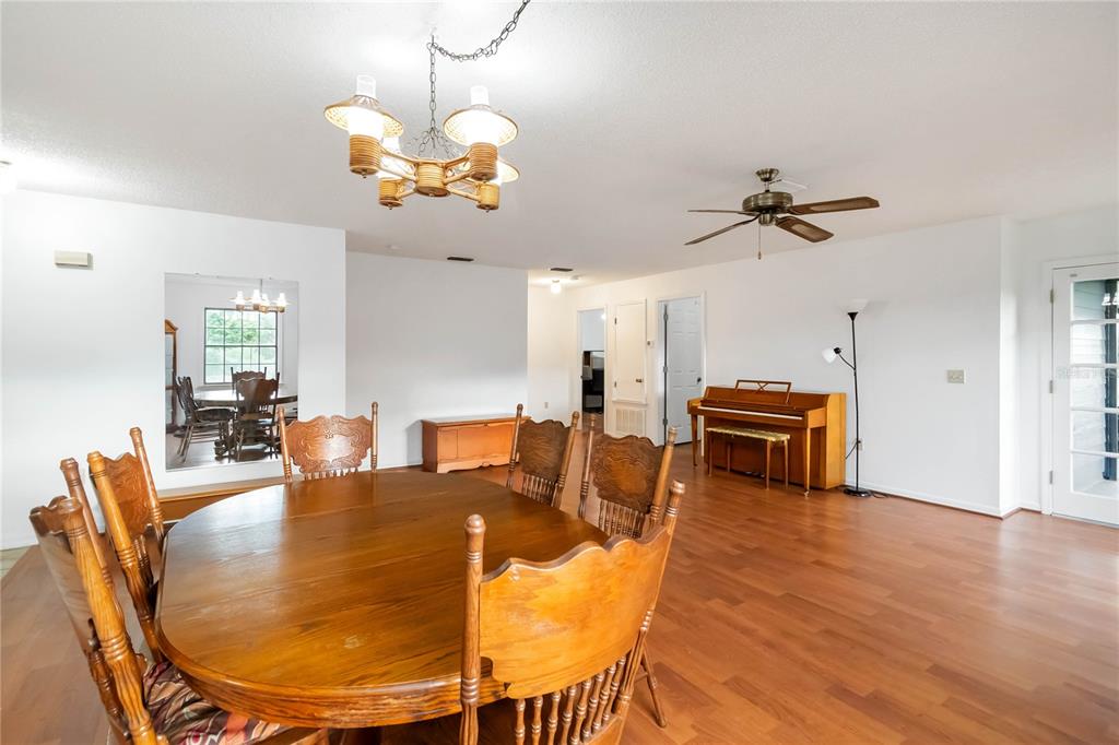 4207 Hamilton Court St. Cloud, FL 34769 - Photo 8 of 30 a dining room with wooden floor a chandelier a glass table and chairs