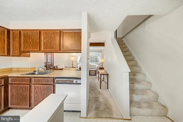 a kitchen with granite countertop a stove a sink and white cabinets with wooden floor