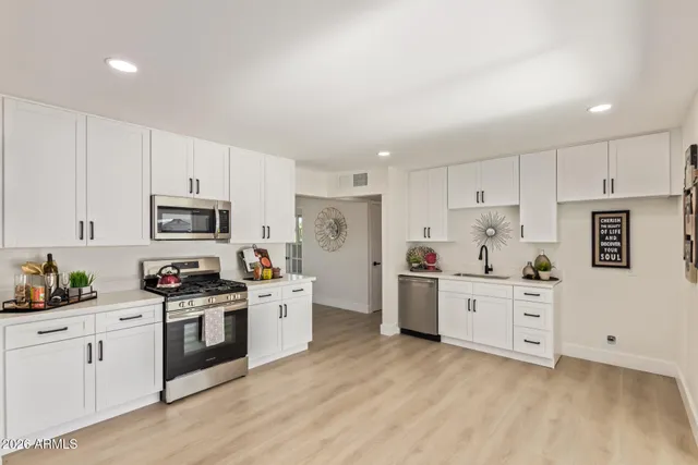 a kitchen with white cabinets stainless steel appliances and sink