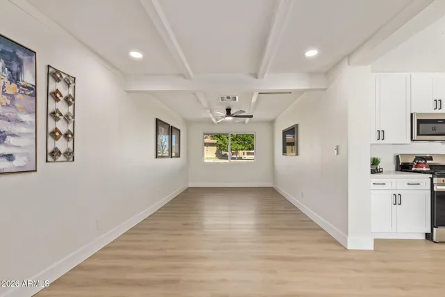 a view of a hallway with wooden floor and a kitchen