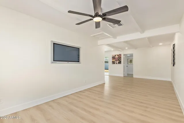 an empty room with wooden floor ceiling fan and windows