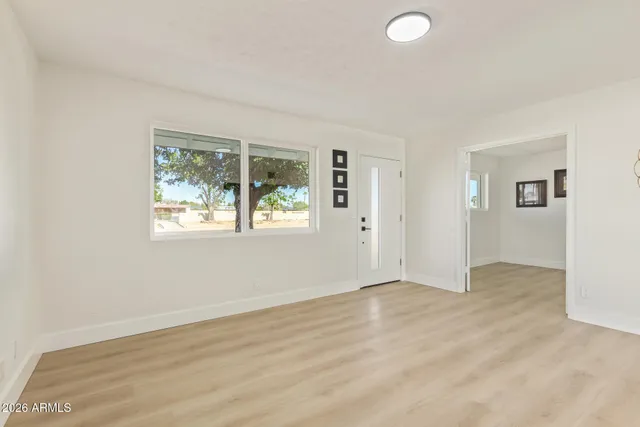 an empty room with wooden floor and windows