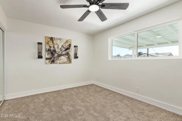an empty room with window and a ceiling fan