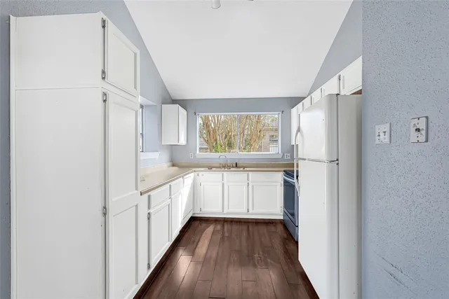 a kitchen with a refrigerator a sink and dishwasher with wooden floor