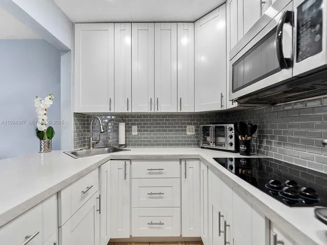 a kitchen with granite countertop white cabinets and white appliances