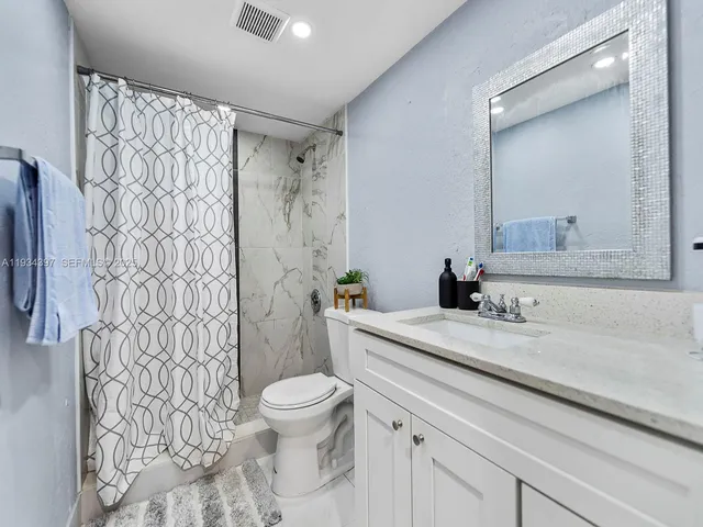 a bathroom with a granite countertop sink a toilet and shower curtain