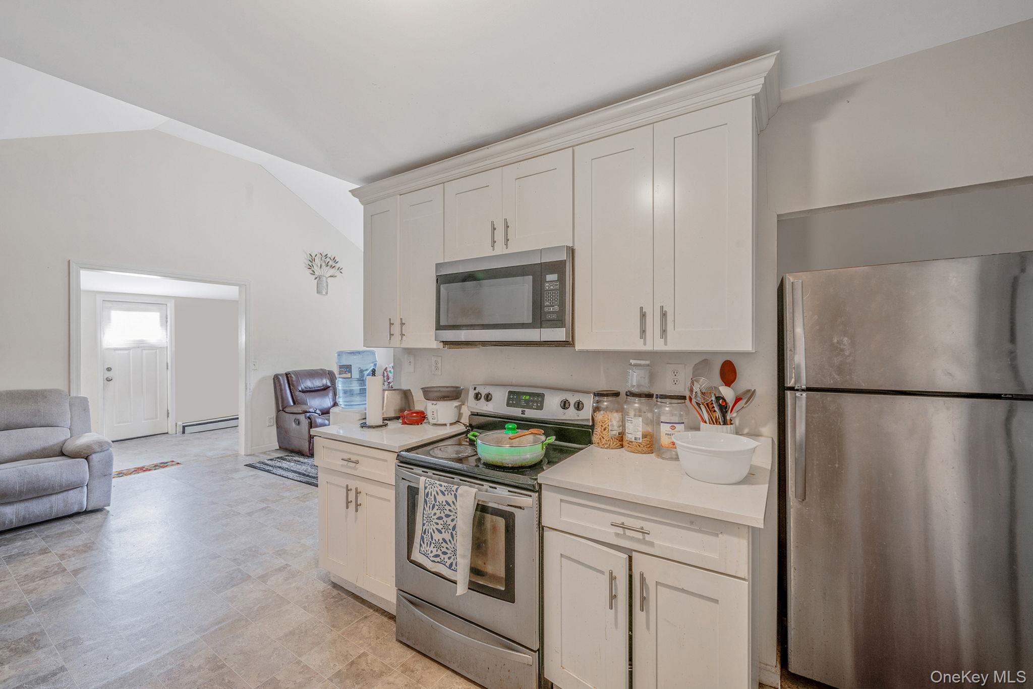 15 Sayville Road Mastic Beach, NY 11951 - Photo 24 of 25 a kitchen with stainless steel appliances granite countertop a refrigerator a stove a sink dishwasher and white countertops with wooden floor