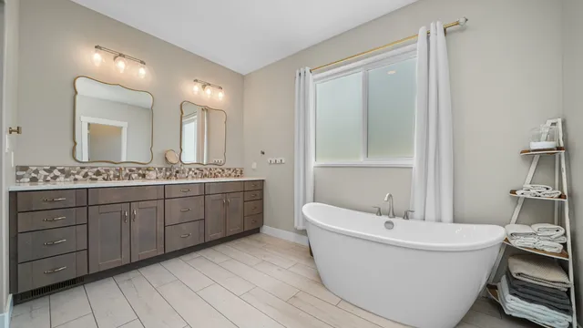 a bathroom with a double vanity sink a mirror and a bathtub