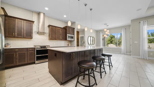 a kitchen with stainless steel appliances kitchen island granite countertop a stove top oven a sink a counter space and cabinets