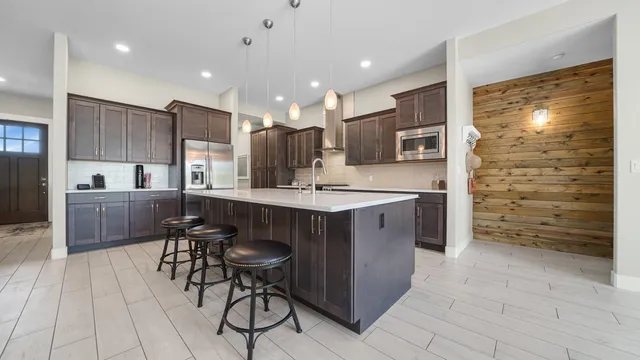 a kitchen with stainless steel appliances a sink a stove a refrigerator cabinets and a dining table