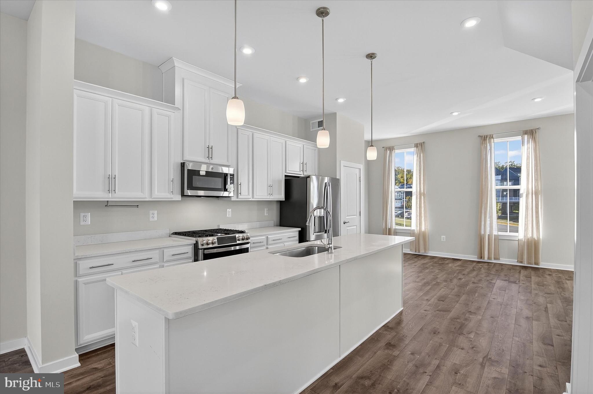 1681 Aspen Poplar Road Dumfries, VA 22026 - Photo 4 of 36 a kitchen with stainless steel appliances granite countertop a sink a stove a refrigerator and white cabinets with wooden floor