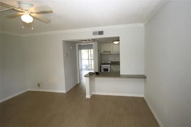 an empty room with chandelier fan and windows