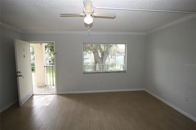 an empty room with wooden floor chandelier fan and windows