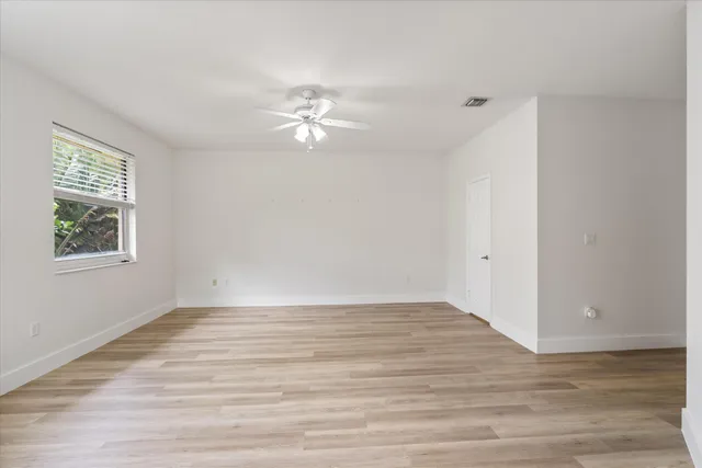 a view of empty room with wooden floor and fan