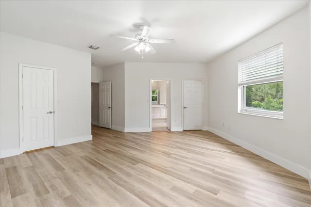 a view of an empty room with window and wooden floor