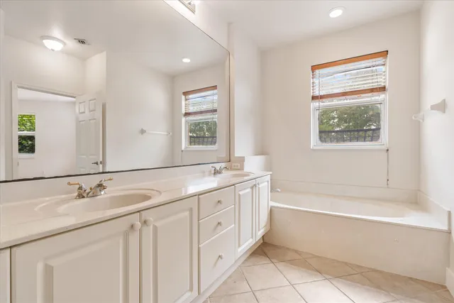 a bathroom with a granite countertop sink a large mirror a bathtub and next to a window