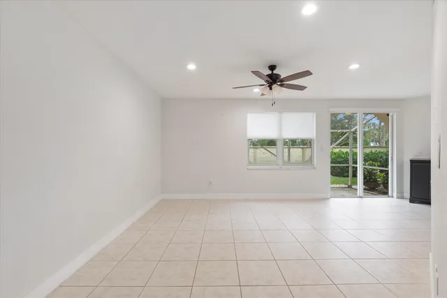 an empty room with windows and chandelier fan