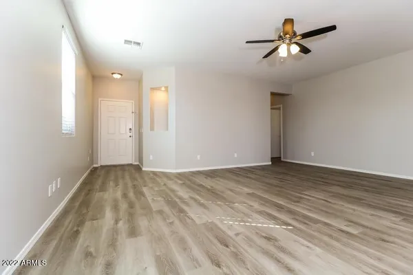 a view of empty room with wooden floor and ceiling fan