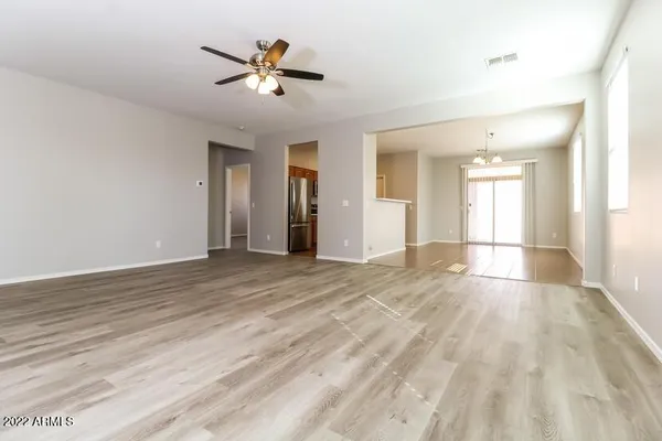 a view of an empty room and window with a ceiling fan