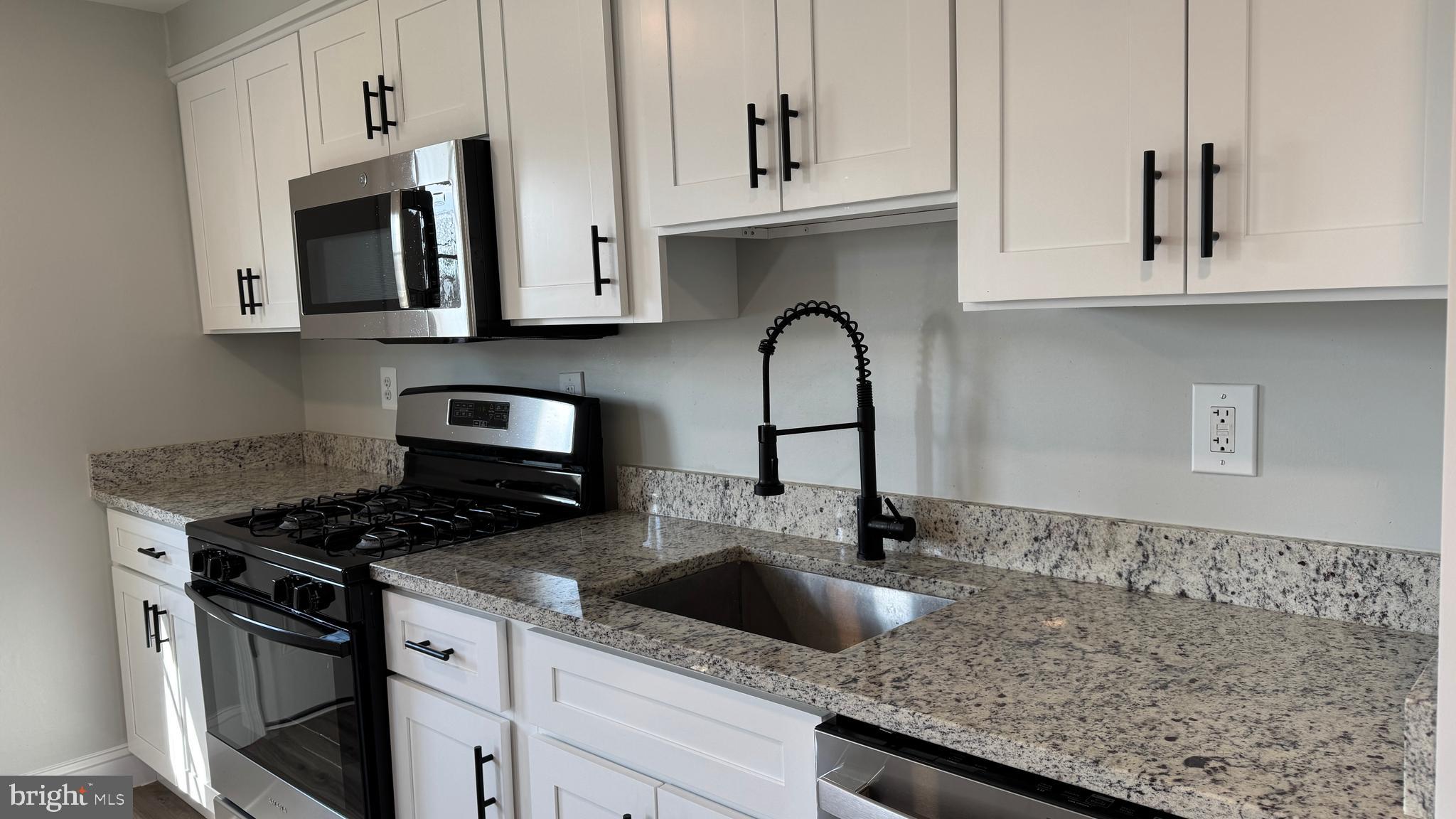 8029 Stratman Road Dundalk, MD 21222 - Photo 7 of 41 a kitchen with granite countertop white cabinets and black appliances