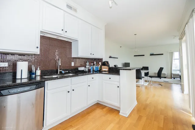 a kitchen with stainless steel appliances granite countertop a refrigerator a stove a sink and white cabinets with wooden floor