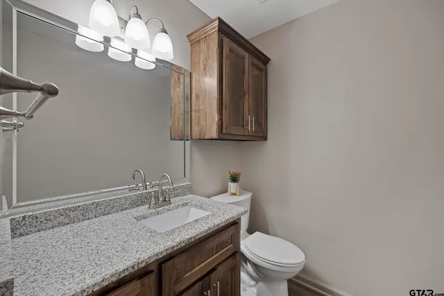 a bathroom with a granite countertop sink a toilet and a mirror