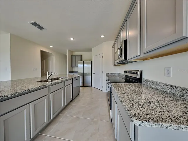 a large kitchen with kitchen island granite countertop a large counter top and wooden cabinets