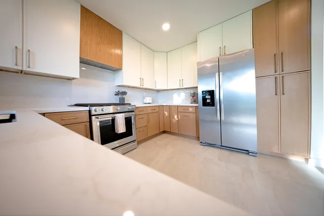 a kitchen with stainless steel appliances granite countertop a refrigerator a sink a stove and white cabinets