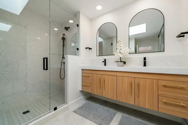 a bathroom with a double vanity sink mirror and shower